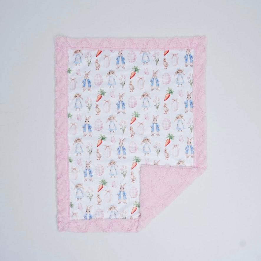 Baby blanket with bunny and carrot pattern on a light gray background