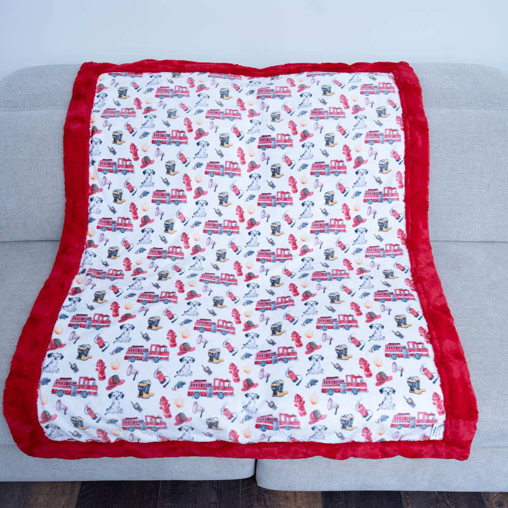 Baby blanket with fire truck pattern on a light gray surface