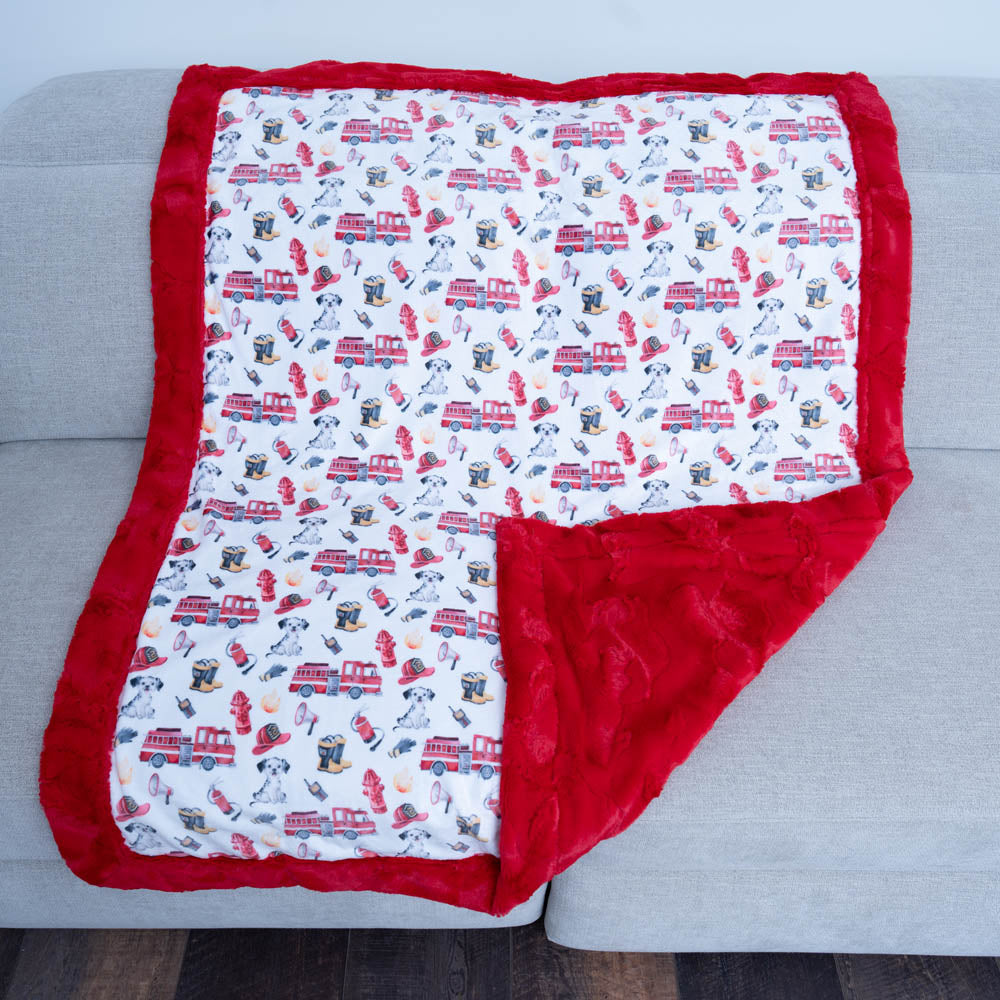 Baby blanket with fire truck pattern on a gray surface