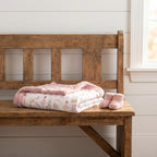 Pink floral minky baby girl blanket styled beside tiny newborn baby shoes