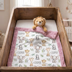 A personalized baby blanket with a white background, pink fuzzy border, and cute animal illustrations, styled inside a rustic wooden bassinet with a plush lion toy.