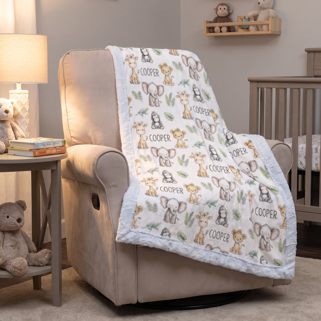 A baby quilted blanket with a cute animal print and the name 'COOPER' is draped over a beige armchair in a nursery setting.