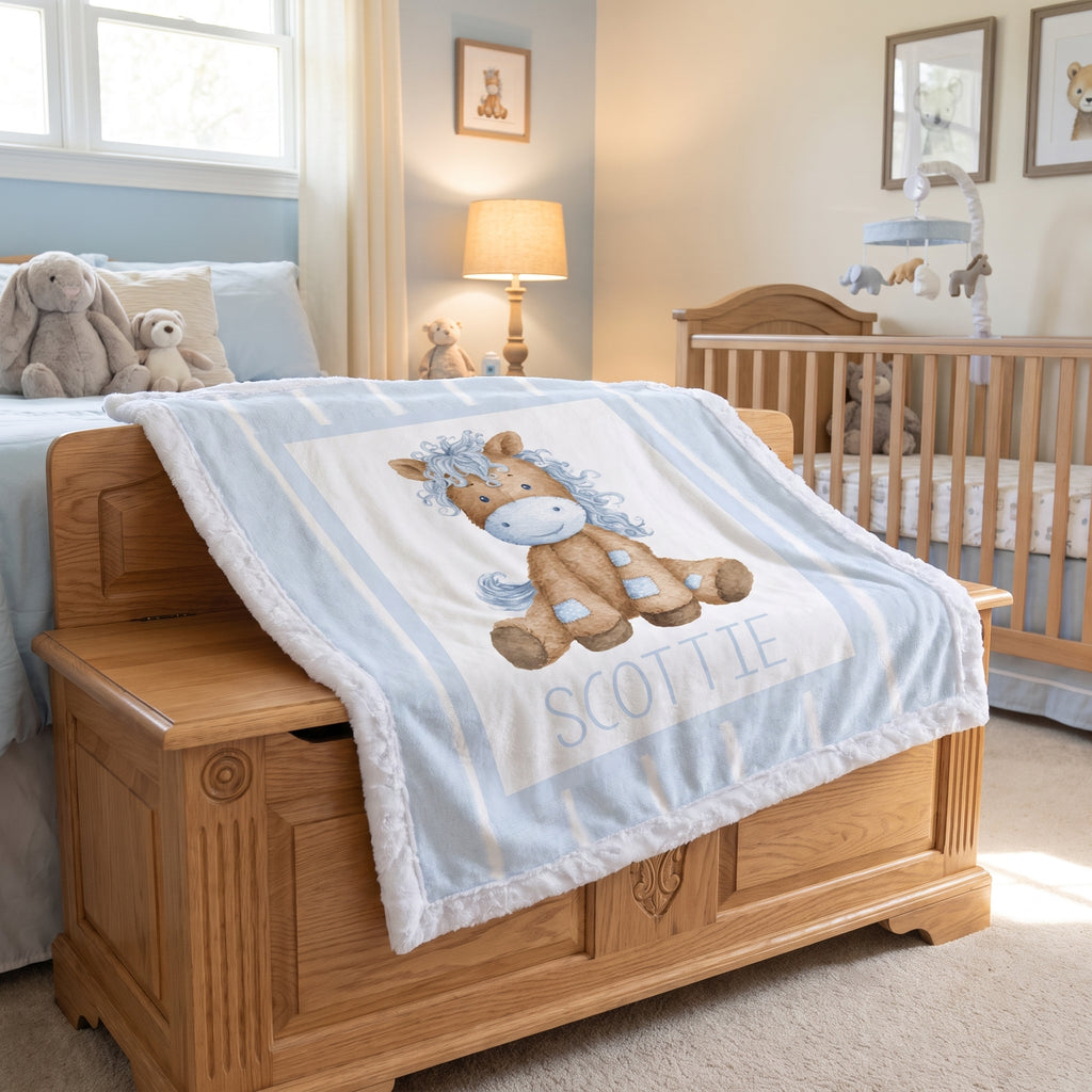 A personalized baby blanket with a cartoon horse and the name 'SCOTTIE' draped over a wooden chest in a nursery setting.