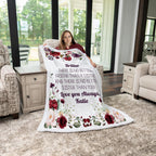 Woman holding a floral blanket with personalized text in a living room.