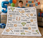 A child holds up a personalized baseball-themed fleece blanket in a living room setting with birthday decorations, including a large number 5 balloon, gifts, and a 'HAPPY BIRTHDAY' banner.