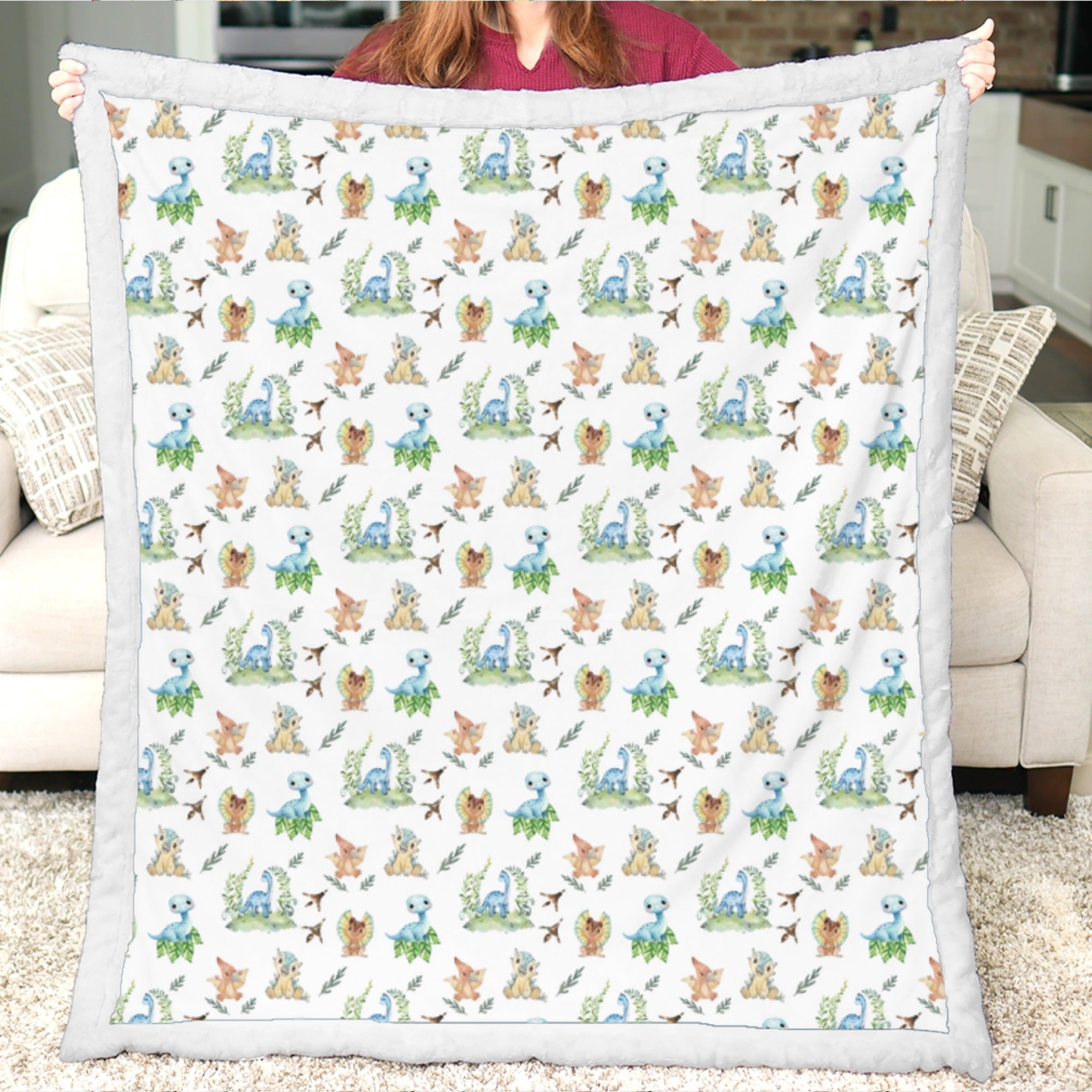Person holding a blanket with a pattern of cartoon animals in a living room.