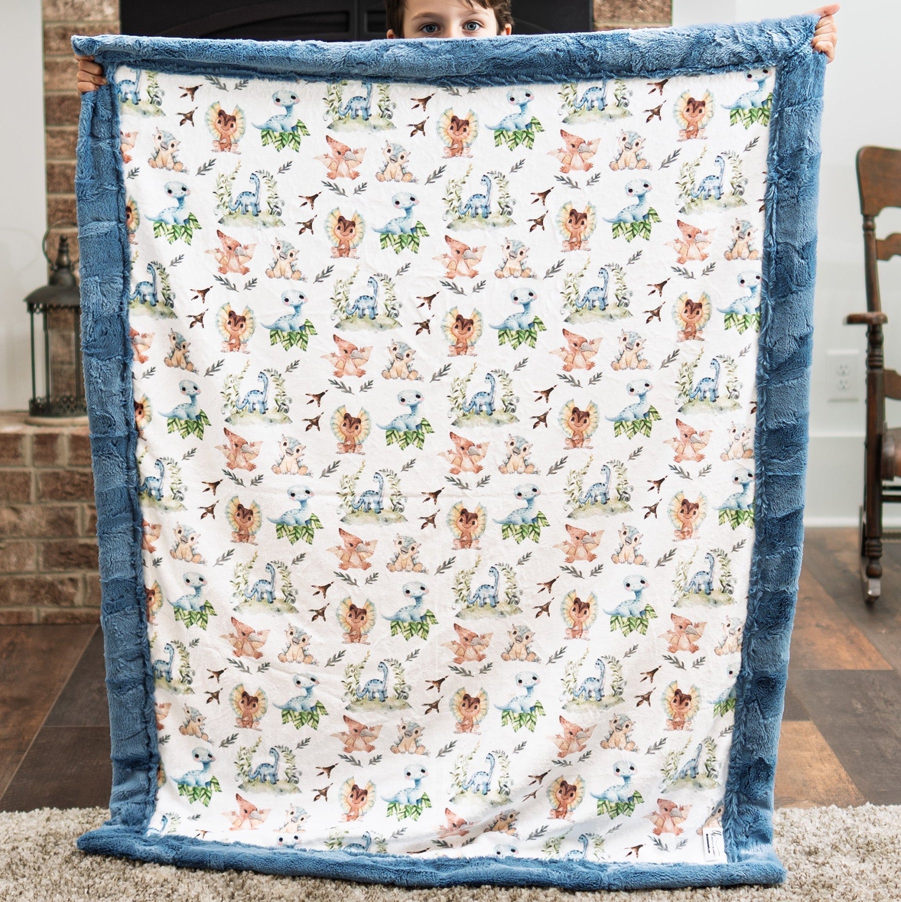 Person holding a blanket with animal pattern in a room with a brick wall and wooden chair.