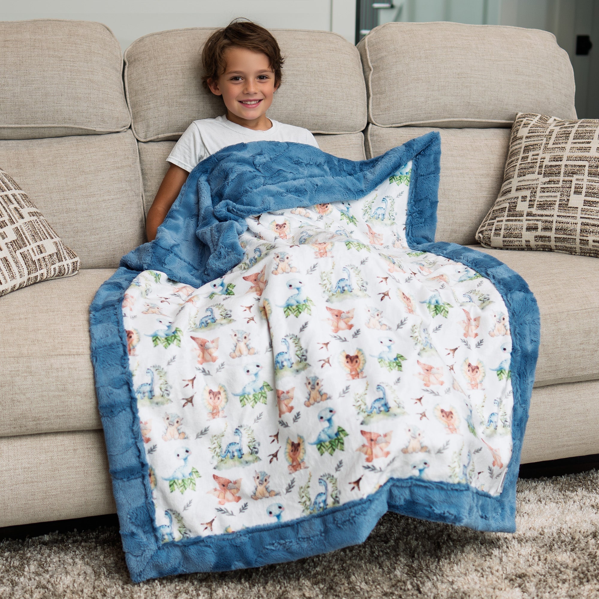 Child sitting on a couch with a colorful blanket featuring animal patterns