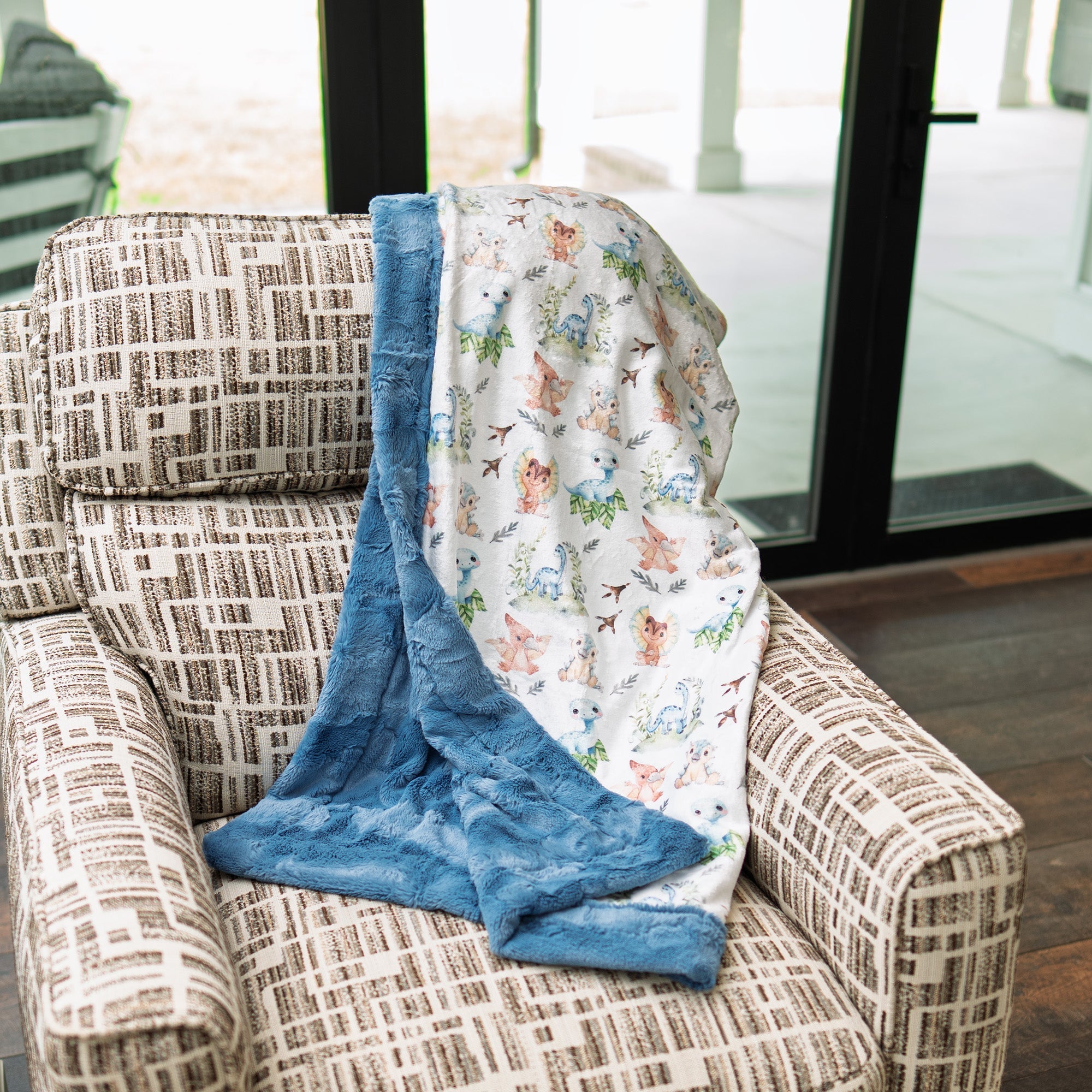 Patterned chair with a blue blanket and a child's comfort blanket featuring animals.