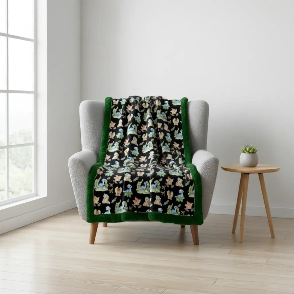 Blanket with dinosaur pattern draped over a chair in a room with a window and small table.