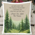 Blanket with forest design and personalized text held by a person in a living room.