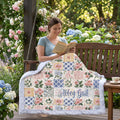 Woman reading on an outdoor porch swing wrapped in a personalized floral minky blanket