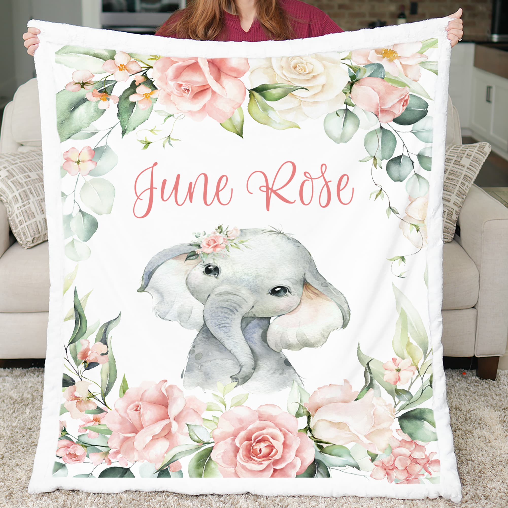 Floral-themed blanket with an elephant design and 'June Rose' text, held by a person.