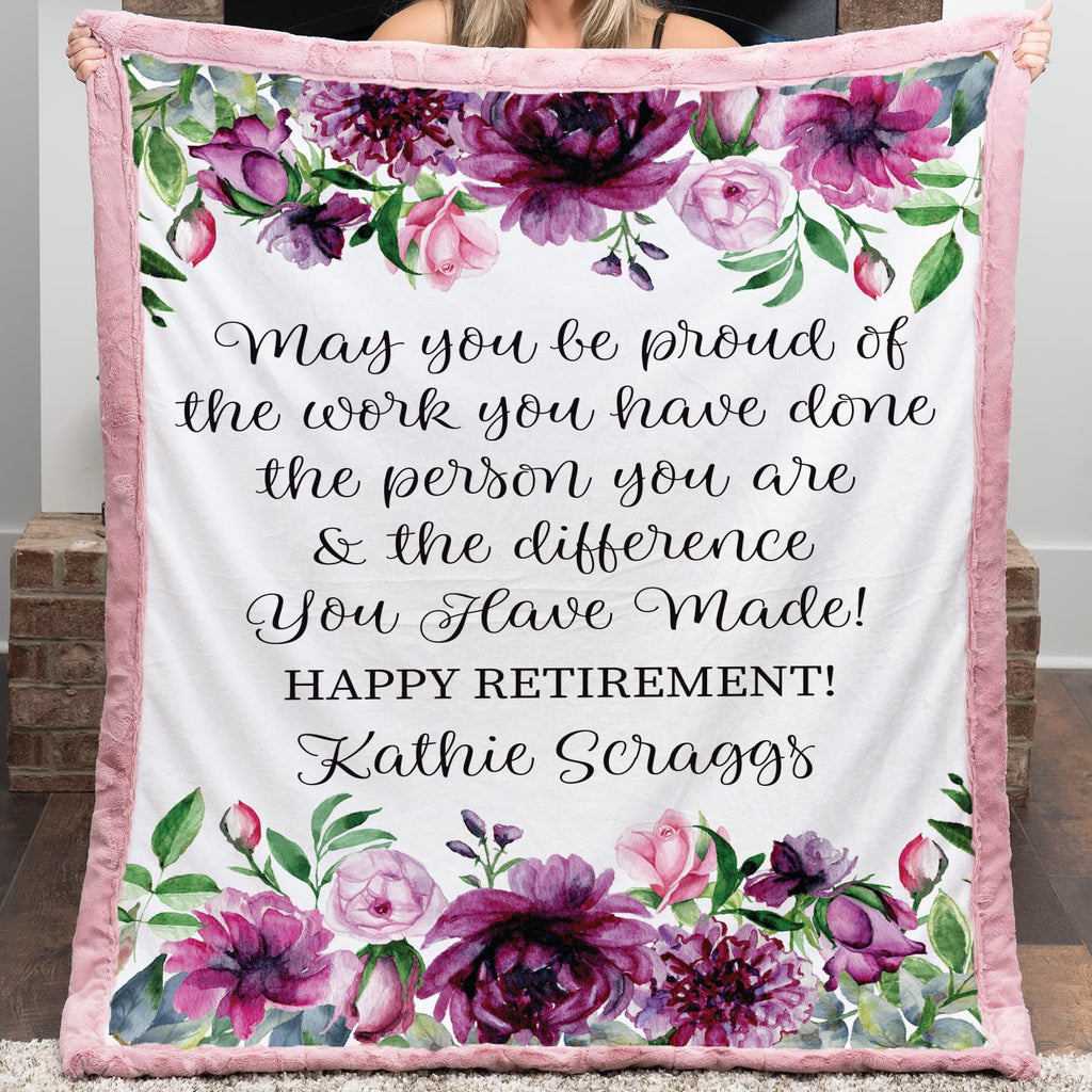 Person holding a floral-themed retirement gift blanket with personalized text.