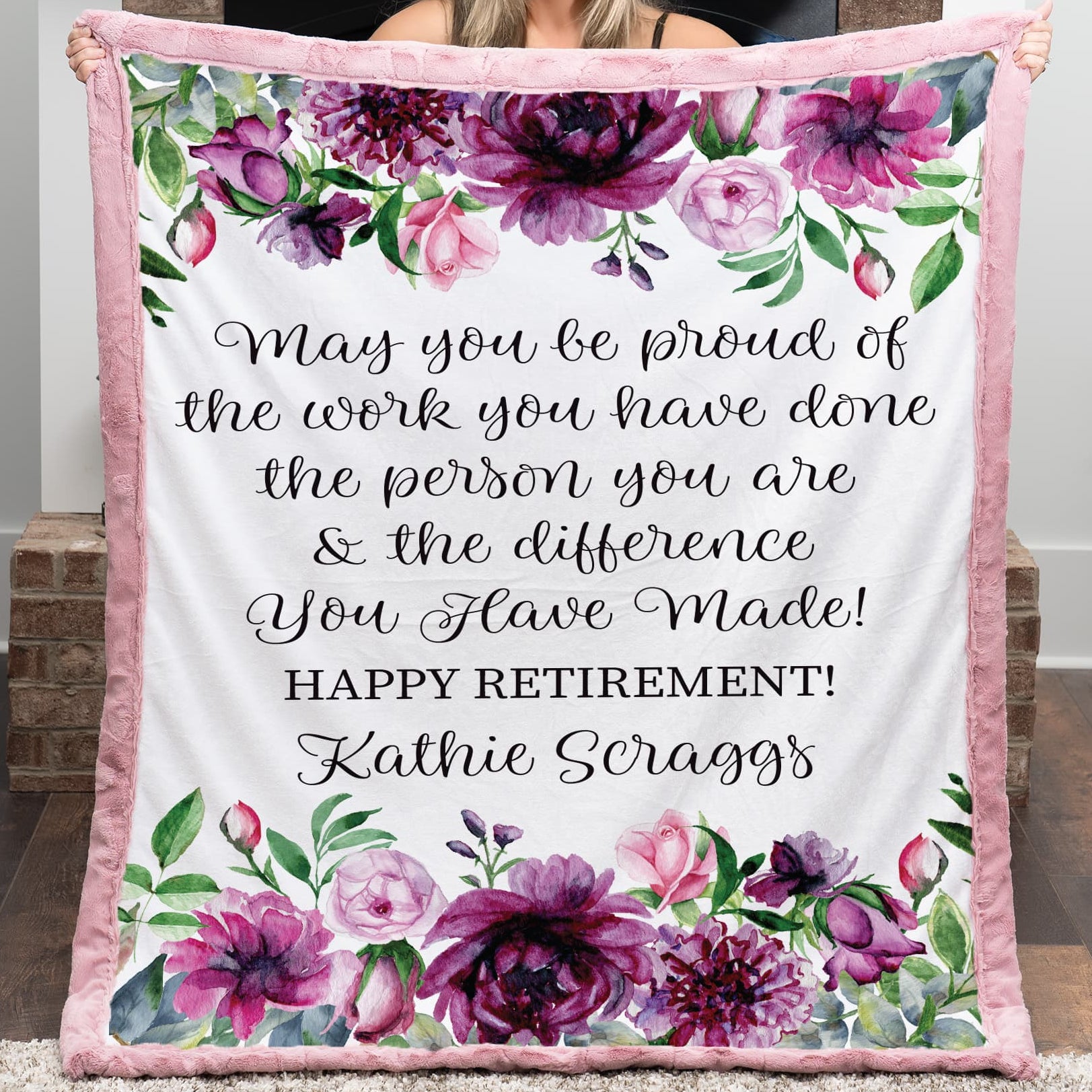 Person holding a floral-themed retirement gift blanket with personalized text.