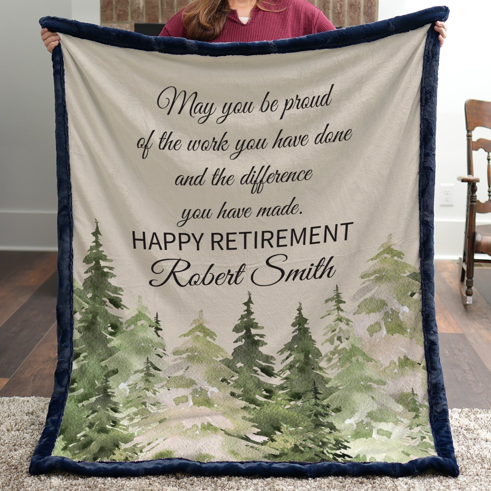Person holding a retirement gift blanket with a scenic design and text.