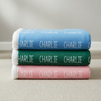Stack of folded towels with 'CHARLIE' branding on a neutral background