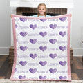 Child holding a blanket with purple hearts and the name 'Elizabeth' on it.