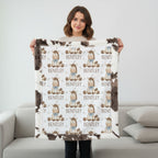 A woman stands in a living room holding up a custom fleece blanket. The blanket features a white background with a repeating pattern of cartoon baby characters wearing blue outfits and brown hats, with the name 'BENTLEY' printed below each character.