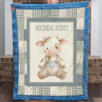 A personalized patchwork quilt held up by a child, featuring a central illustration of a cute cow in overalls with the name 'MICHEAL SCOTT' printed above it. The quilt has a blue border and a patchwork design with blue, beige, and gray tones.