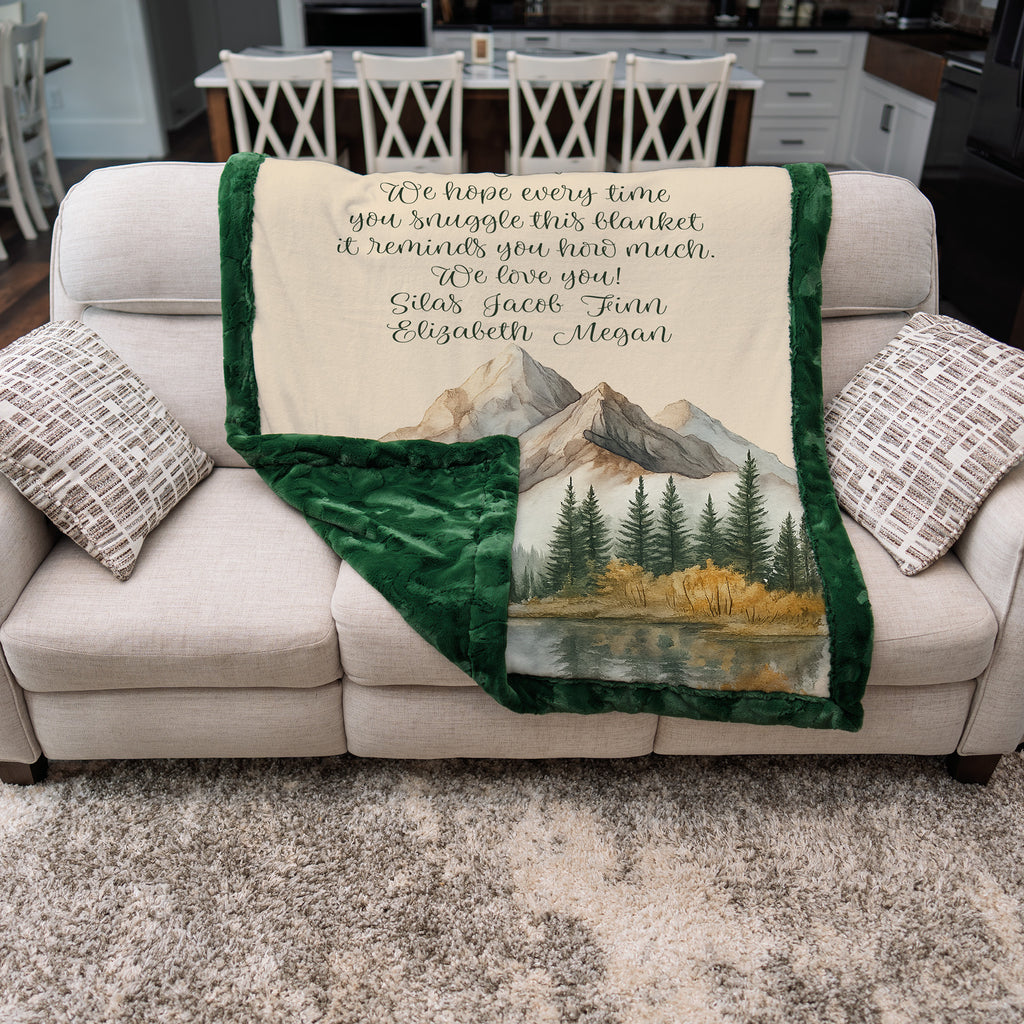 Blanket with scenic design and personalized text on a couch in a living room setting.