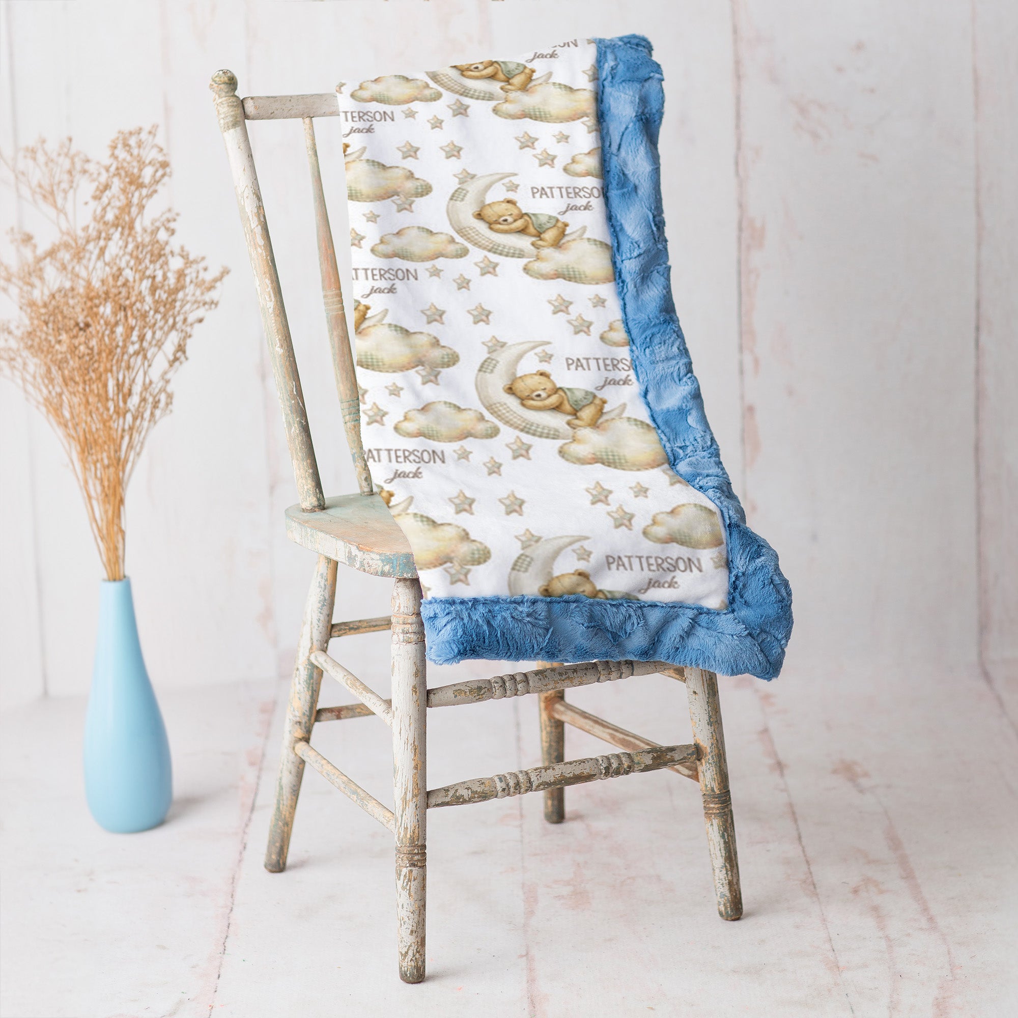 Bear and moon baby blanket with blue minky trim draped over vintage rustic chair