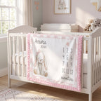 A personalized baby crib bedding set featuring a white and pink checkered blanket with a bunny graphic, the name 'Aurora Jean', and a monthly counting track, displayed in a bright, modern nursery.