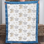 A custom minky blanket held up by a child, featuring a white center printed with blue and beige carousel illustrations and the names 'Frankie James', surrounded by a blue plush border.