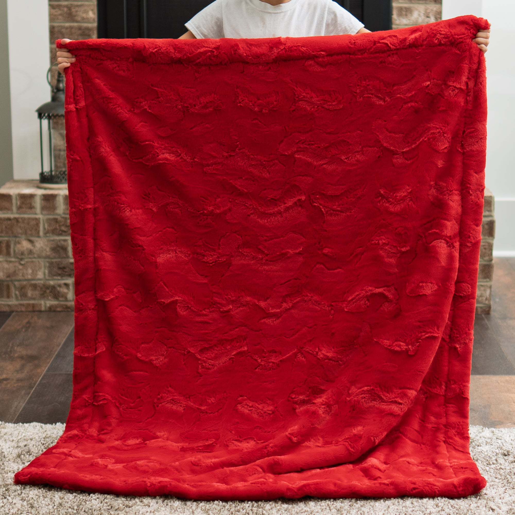 Red Luxe Cuddle back panel of firefighter baby blanket, held up showing textured fabric