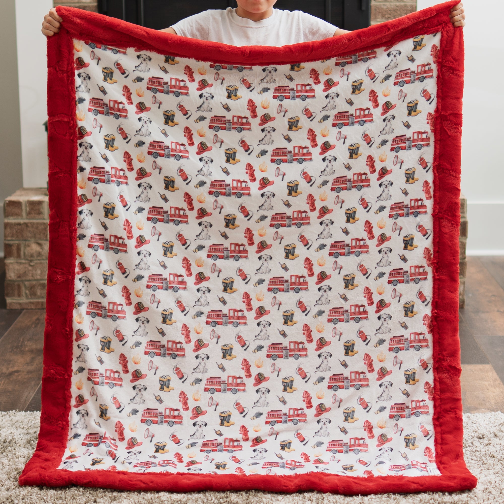 Firefighter Luxe Cuddle baby blanket held up, fire truck and Dalmatian watercolor print with red border