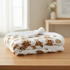 Folded blanket with teddy bear pattern on a wooden surface