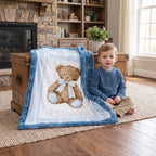 A child sits on a rug beside a personalized plush blanket in a cozy living room. The blanket has a blue fuzzy border and a white center printed with a teddy bear and the name CHRISTOPHER.