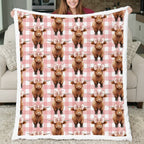 Person holding a blanket with Highland cow pattern on a checkered background