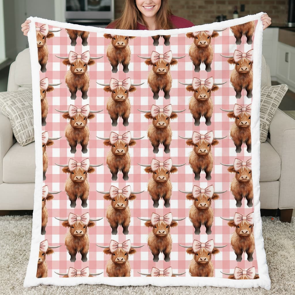 Person holding a blanket with Highland cow pattern on a checkered background
