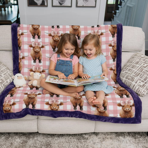 Two children sitting on a couch with a blanket featuring cow patterns, reading a book.