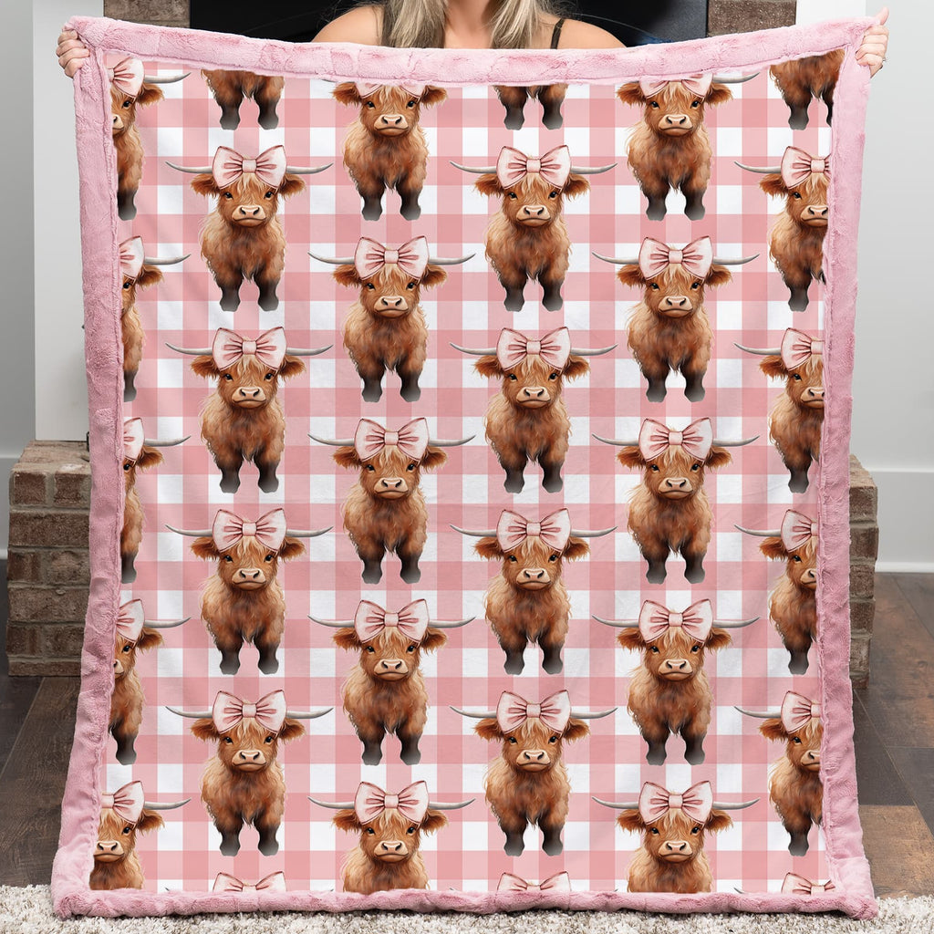 Person holding a pink blanket with Highland cow pattern