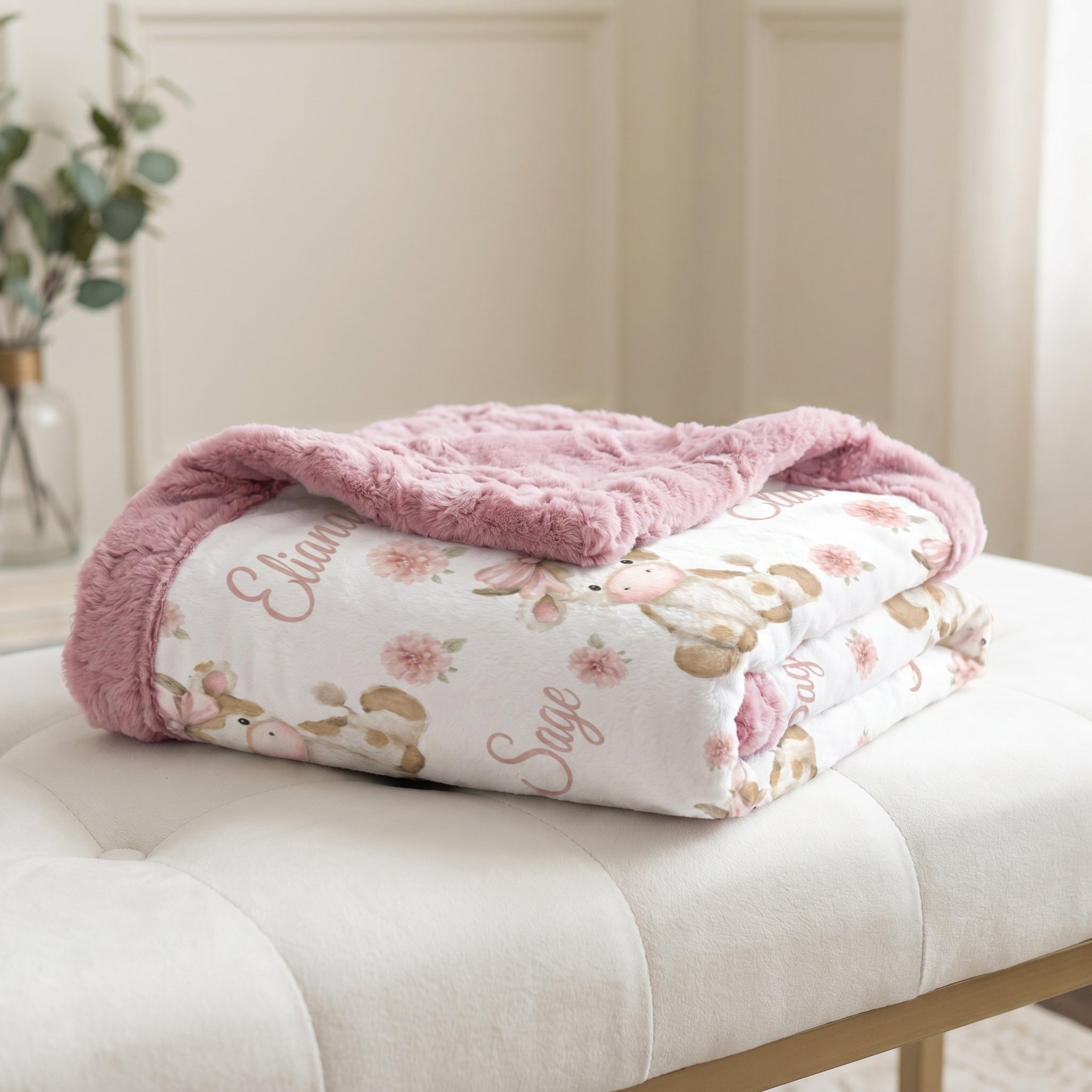 Highland cow minky baby blanket folded on bench, showing pink fur backing