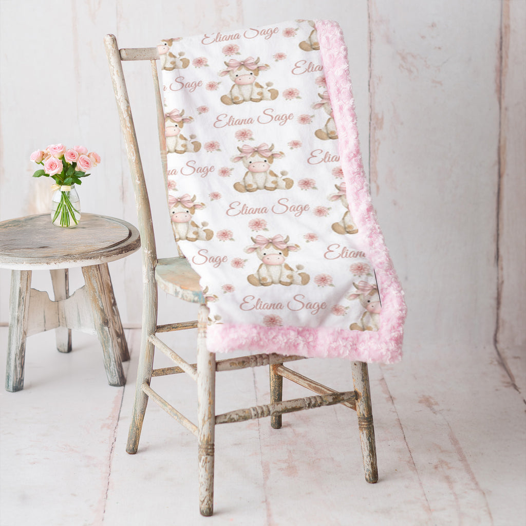Highland cow minky blanket draped over rustic chair, pink rosette fur backing