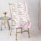Highland cow minky blanket draped over rustic chair, pink rosette fur backing