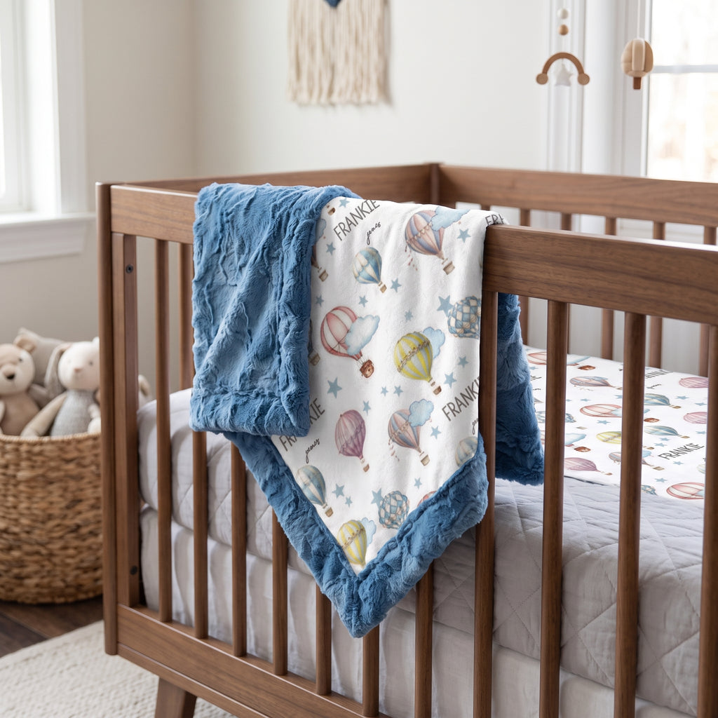 Hot air balloon minky baby blanket draped over crib rail in nursery