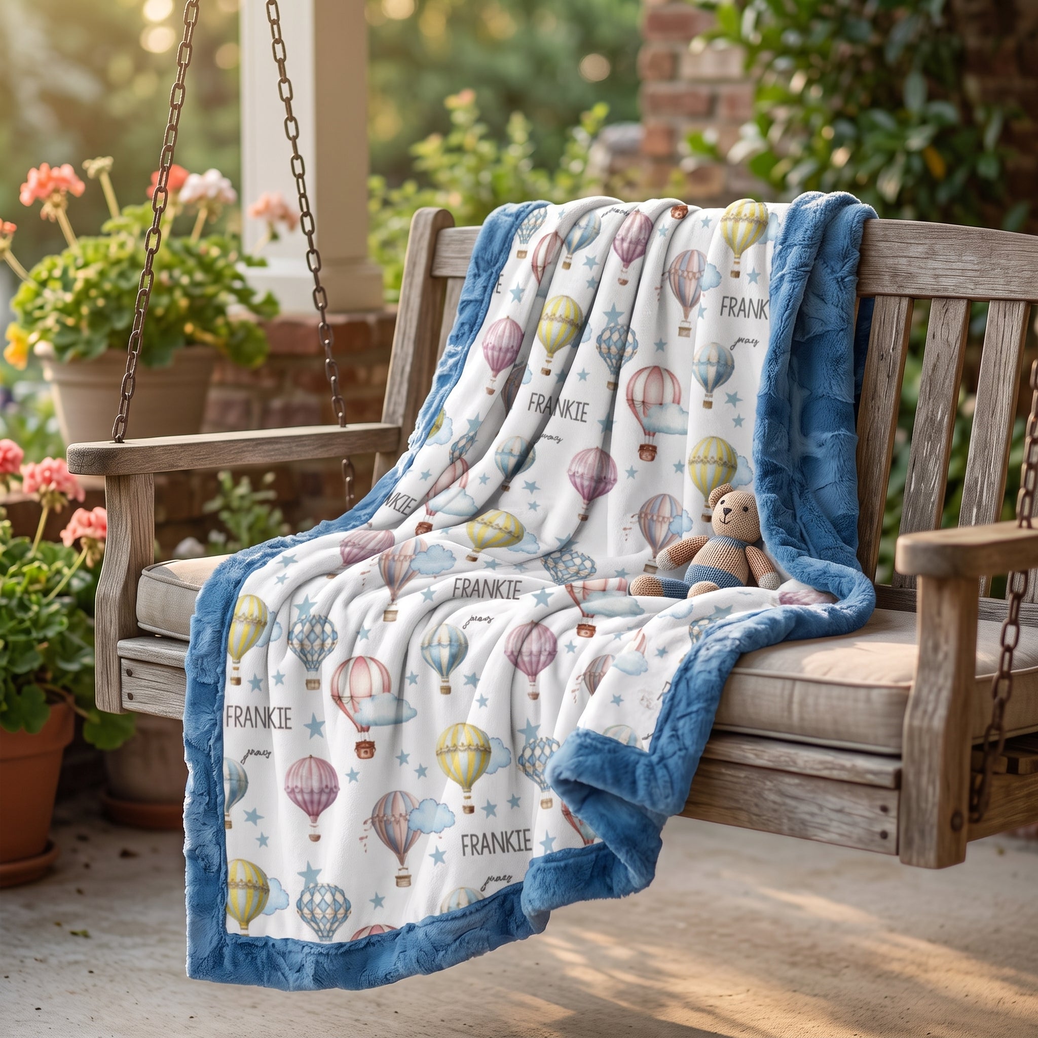 Personalized baby blanket with blue minky border and teddy bear on outdoor porch swing