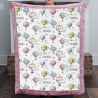 Woman holding up personalized hot air balloon baby blanket with pink minky border
