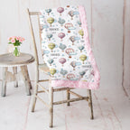 Personalized hot air balloon blanket with pink rosette minky backing on rustic chair