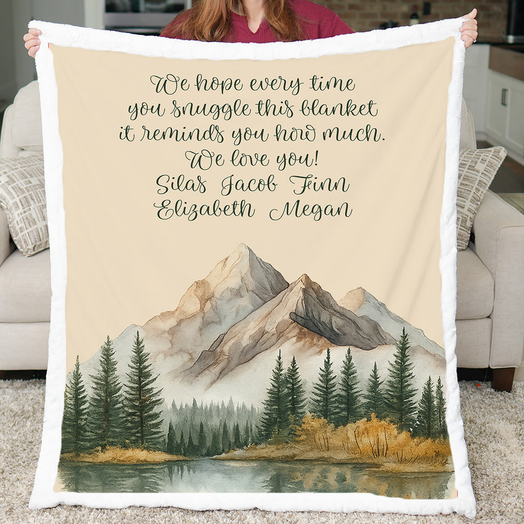 Blanket with mountain and forest design held by a person in a living room.