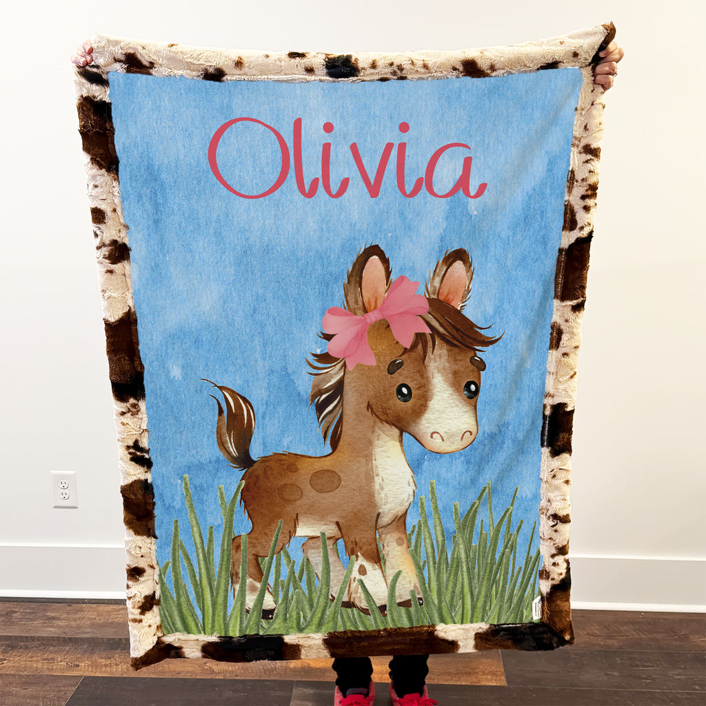 Blanket with a horse design and the name 'Olivia' on a blue background