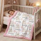 A baby sleeping in a white wooden crib, covered with a white blanket featuring a repeating pattern of gray bunny illustrations, the text 'Aurora JEAN', and a soft pink fuzzy border.