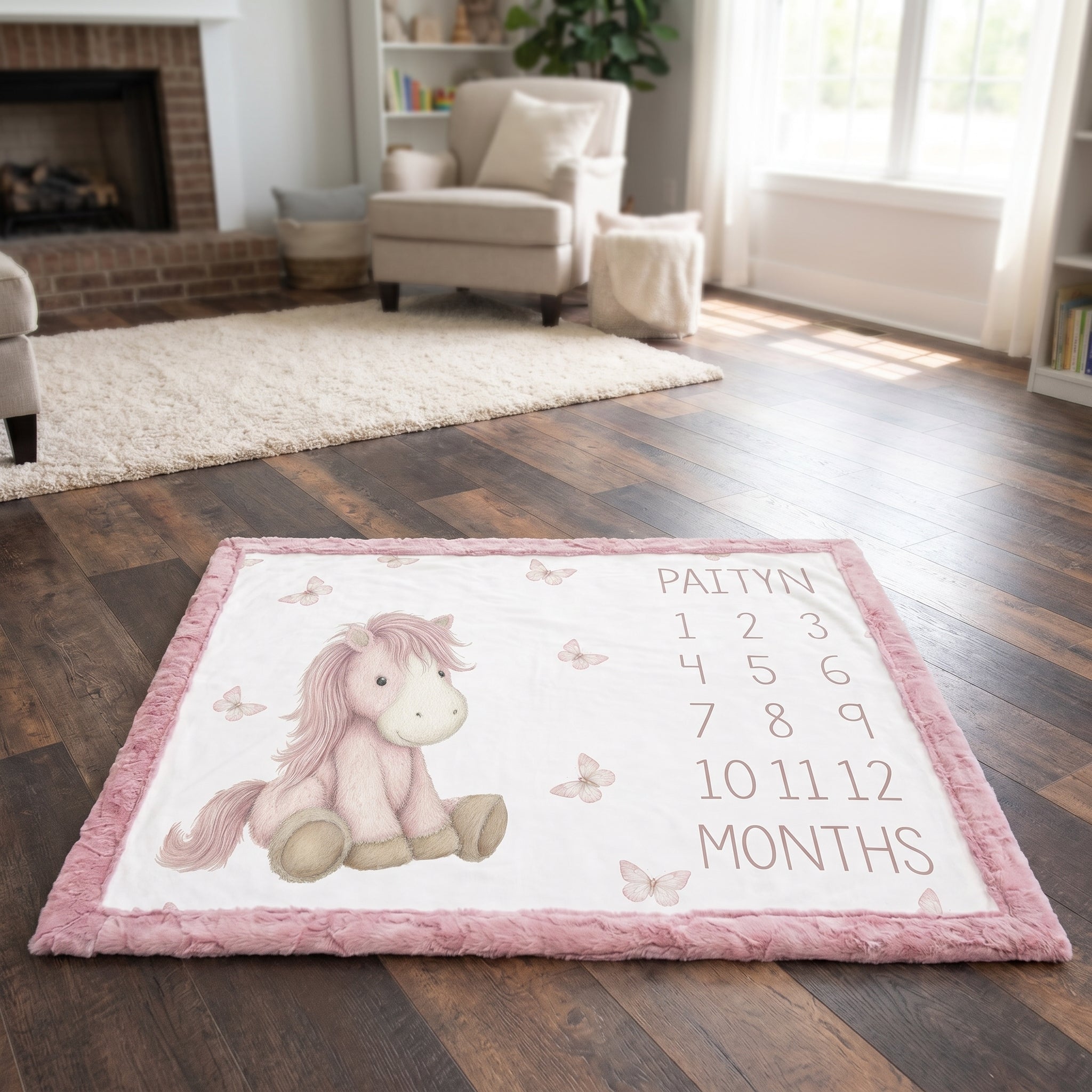A personalized baby milestone rug featuring a pink cartoon horse, butterflies, and the name 'Paltyn' with months 1 through 12, placed on a dark wood floor in a cozy living room.