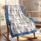 A plush baby blanket with a blue border and a white center printed with teddy bear illustrations and the name 'BENTLEY' is draped over a wooden rocking chair in a softly lit nursery.