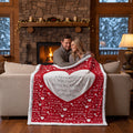 A couple hugging under a red and white fleece blanket with a large white heart in the center that reads 'I'm hugging you with this blanket I love you. Birthday'.