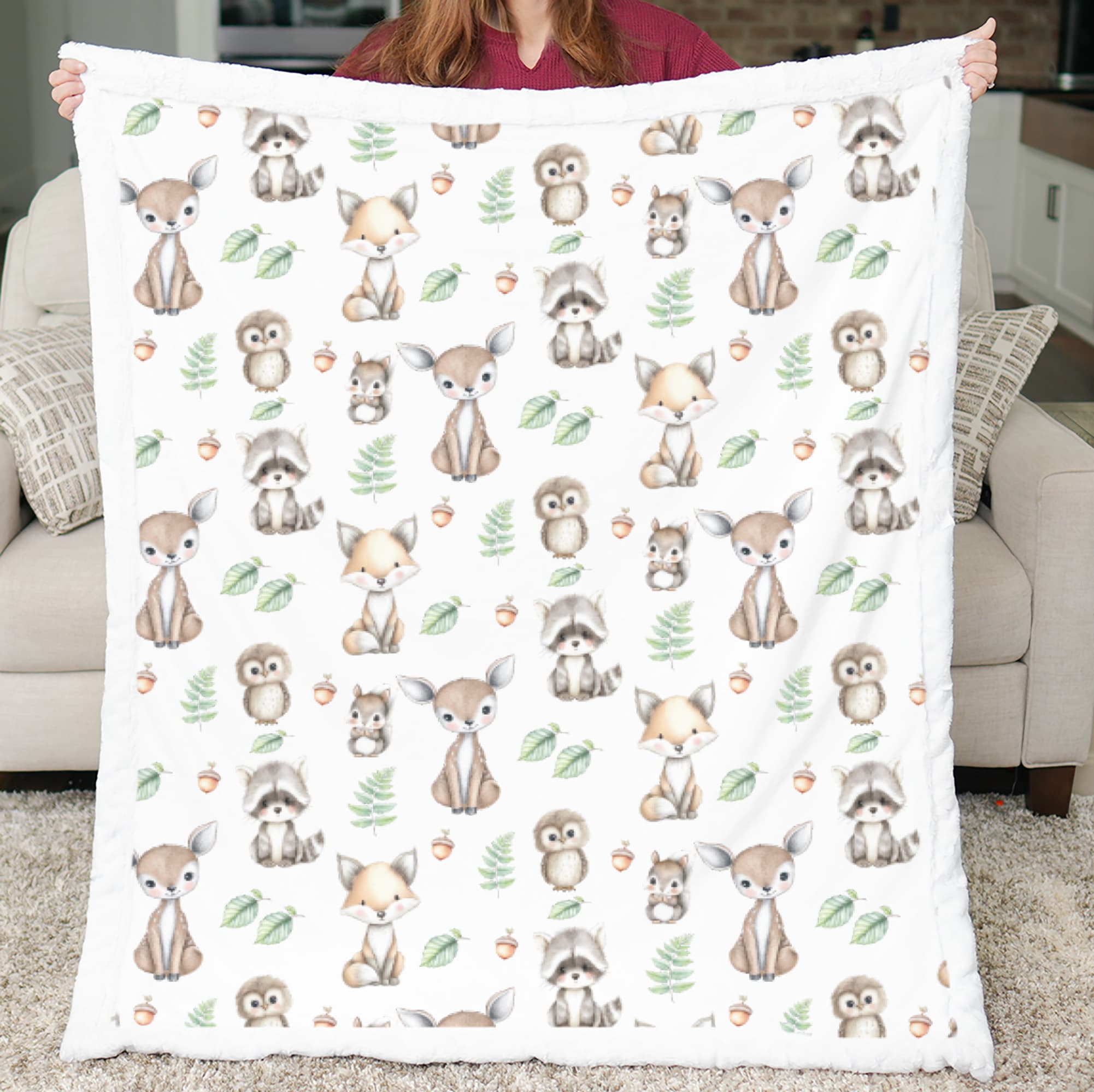 Person holding a blanket with forest animal pattern in a living room.